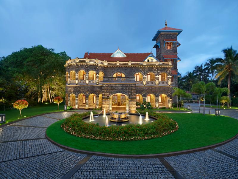 The Leela Kovalam exterior at dusk, perched dramatically on cliffs overlooking the Arabian Sea